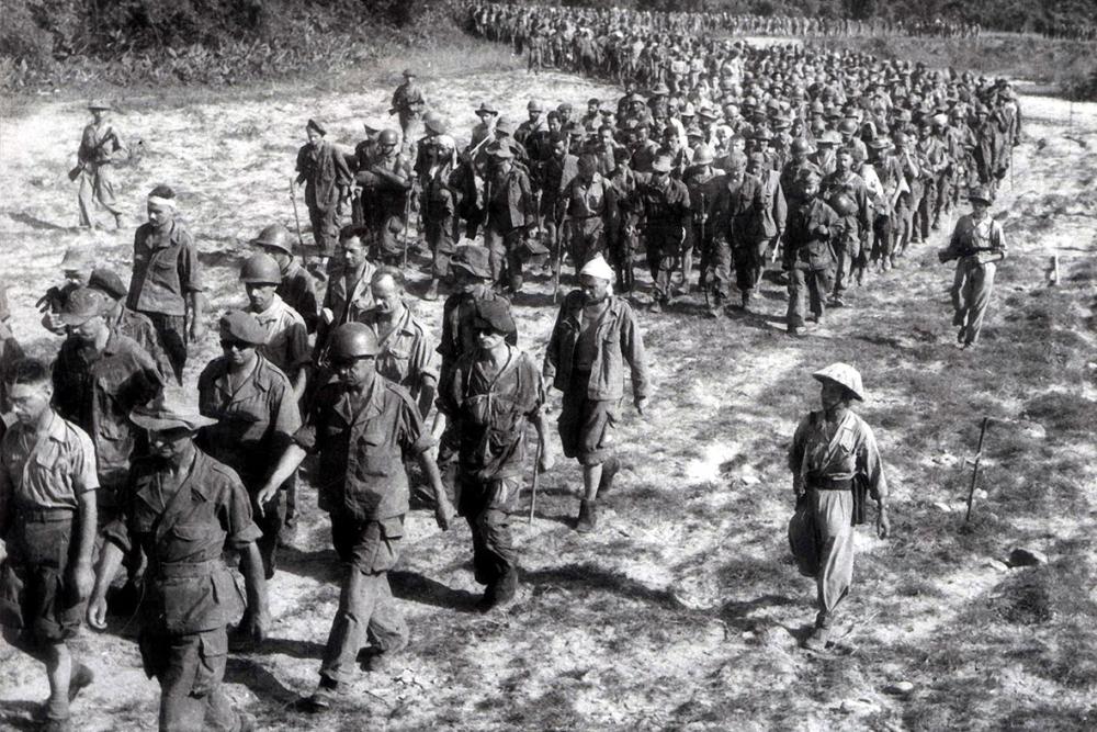 Captured French soldiers, escorted by Vietnamese troops, walk to a prisoner-of-war camp in Điện Biên Phủ