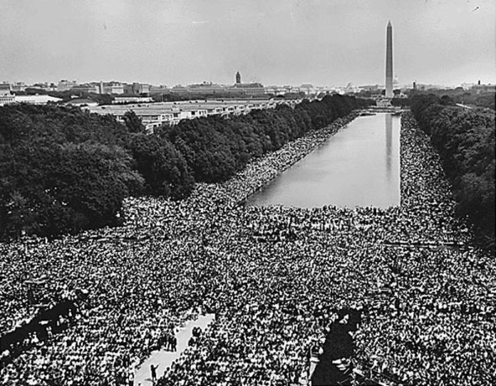 View of the crowd at 1963 Civil Rights March on Washington, D.C. estimated at 250,000 people. A wide-angle view of marchers along the mall, showing the Reflecting Pool and the Washington Monument.